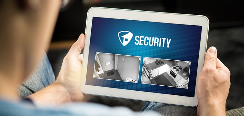 Man using home security system and application in tablet. Watching protection camera live footage inside a house or apartment.